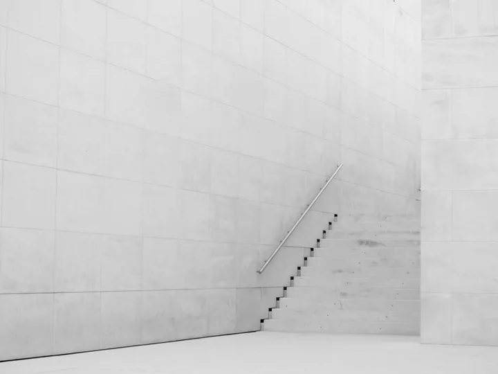 Beispielfoto: Helle Steintreppe mit Metallhandlauf zwischen großformatig verkleideten Steinwänden.